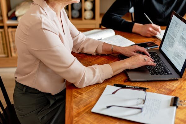 Two people working on laptops with documents; illustrating vendor due diligence process in selling a business in Australia.