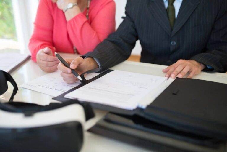 Man and woman sitting at table reviewing documents, discussing steps after completing a business sale.