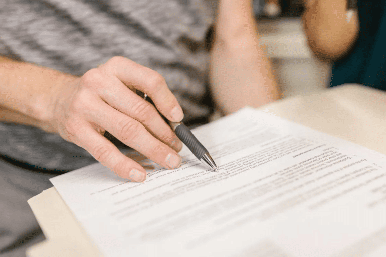 A person reviews a share purchase agreement document, focusing on key terms relevant to Australian transactions, using a pen.
