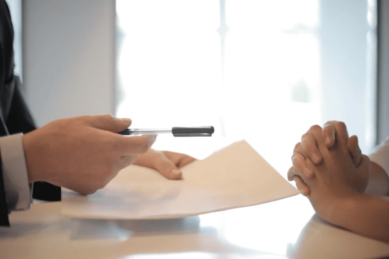 A business owner is handed a pen and documents, symbolizing steps in selling your RTO, a business owner's guide.