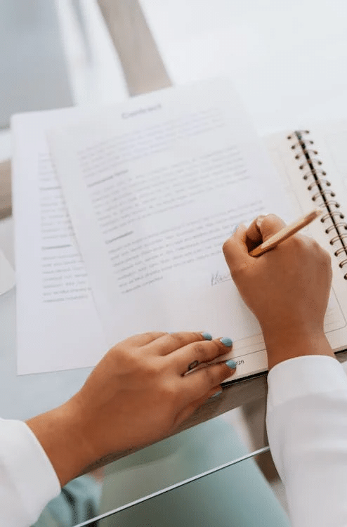 Person signing a contract, highlighting legal requirements for buying a dermatology practice in NSW.