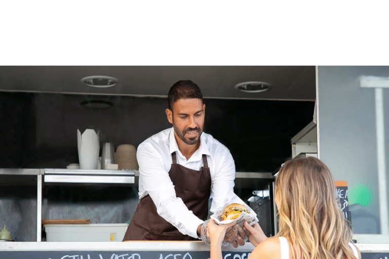 Man selling burger from a food truck to a woman, illustrating entrepreneurship in buying a food truck business.