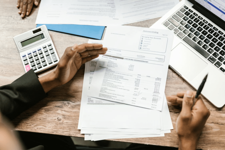 Business sale documents and financial statements being reviewed near a laptop, illustrating a sale of a business as a going concern.