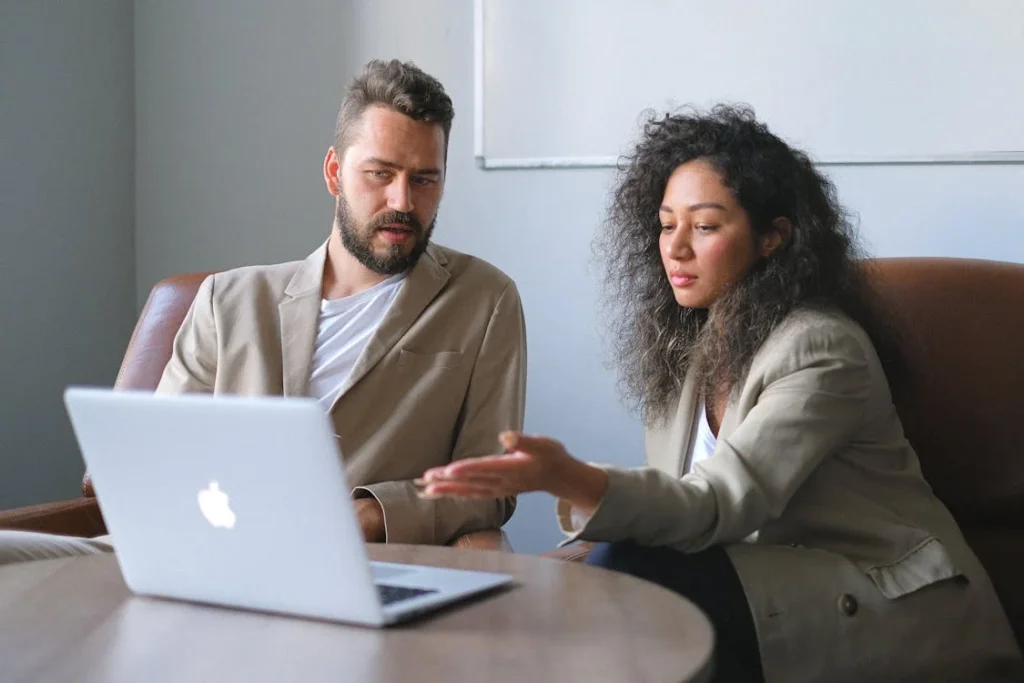 Two professionals discussing a Voluntary Deregistration Guide on a laptop for company deregistration.
