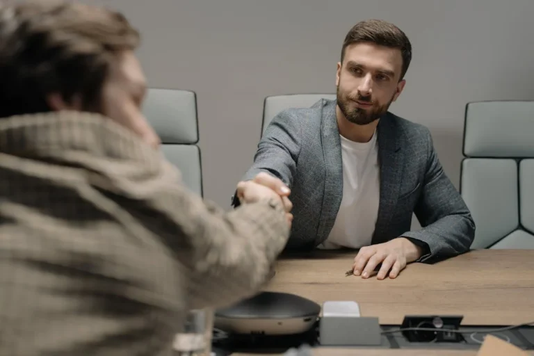 Two men shaking hands across a conference table, symbolising a real estate agreement: When Can Deposits be Forfeited?