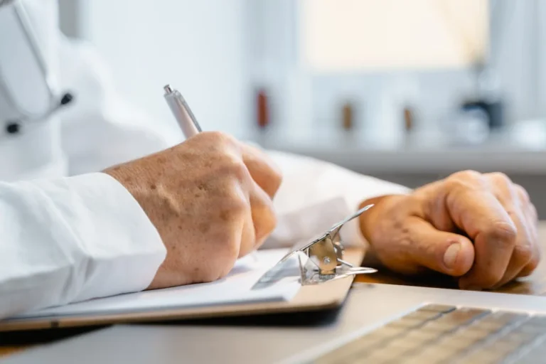 Person signing paperwork, illustrating legal steps for selling a physiotherapy practice in NSW.
