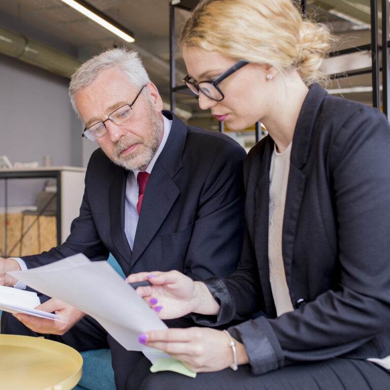 Professionals discussing document transfer in intellectual property business sale.