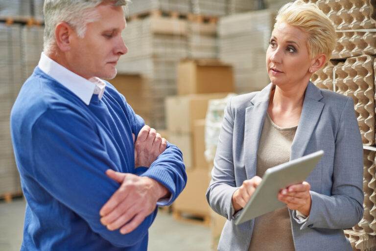 Business professionals discuss vendor warranties and purchase options in a warehouse setting.